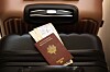 French passport and travel tickets lying on a black suitcase.