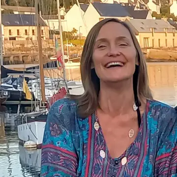 Smiling woman in a patterned top beside moored boats at a marina