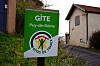 Gîtes de France sign beside a rural lane and houses in Puy-de-Dôme, France.