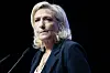 Marine Le Pen speaks at a podium against a dark background in Châlons-en-Champagne, France.