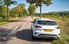 British-registered white car on a tree-lined rural road in the French countryside