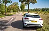 British-registered white car on a tree-lined rural road in the French countryside
