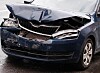 Dark blue car with a crumpled bonnet, broken grille and damaged front bumper after a crash.