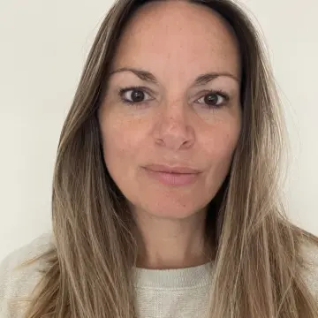 Woman with long brown hair posing in a close-up portrait against a plain background