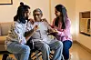 Young asian siblings care for their elderly father in a wheelchair at home.