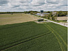 Green and harvested fields beside a rural road under a cloudy sky