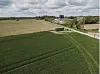 Green and harvested fields beside a rural road under a cloudy sky