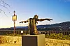 Bronze statue with outstretched arms overlooking a mountain valley