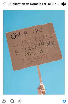 Hand holding a French placard calling for a future to build against a blue sky