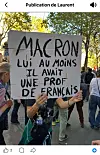 Protester holds a handwritten French sign criticising Macron during a street demonstration.