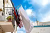 Laundry hangs from a Mediterranean balcony beneath a bright blue sky.