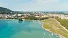 Aerial view of Le Pâquier park beside turquoise Lake Annecy and the city beyond.