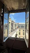 Charred room framing an open window overlooking historic slate-roofed buildings