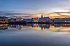 Bayonne waterfront illuminated at Christmas, with the city skyline reflected in calm water at sunset.
