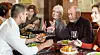 Family members gather around a restaurant table for lunch with food and drinks.